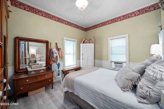 bedroom featuring hardwood / wood-style flooring, ceiling fan, crown molding, and multiple windows