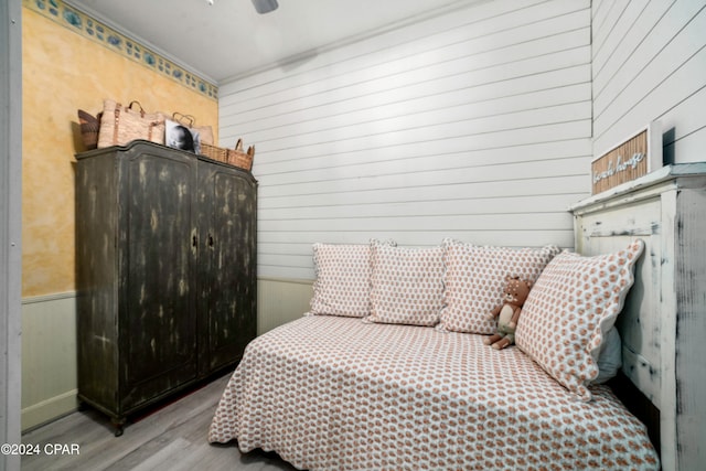 bedroom with light wood-type flooring, ceiling fan, and wood walls