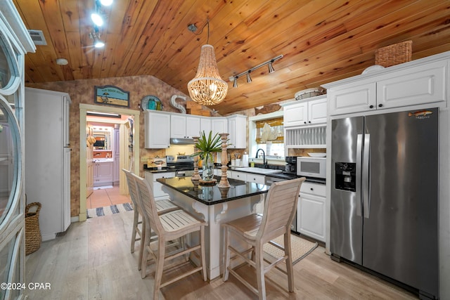 kitchen featuring light wood-type flooring, stainless steel appliances, pendant lighting, white cabinetry, and lofted ceiling