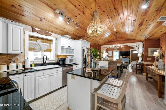 kitchen with pendant lighting, lofted ceiling, white cabinets, sink, and stainless steel appliances