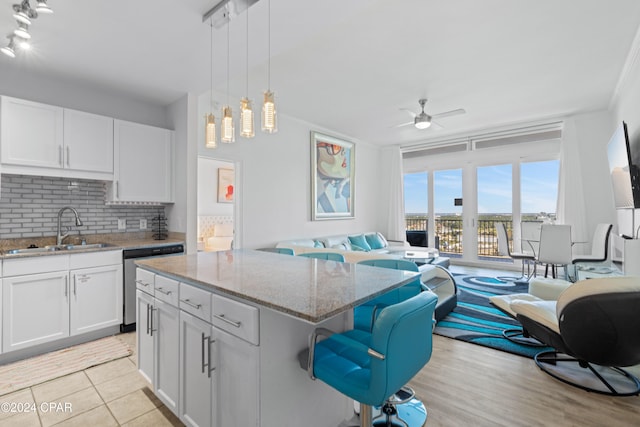 kitchen featuring dishwasher, a kitchen island, white cabinetry, and sink