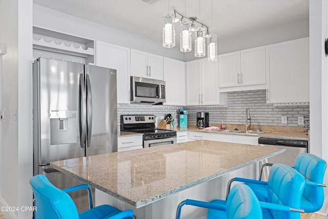 kitchen with a kitchen bar, a kitchen island, white cabinets, and appliances with stainless steel finishes