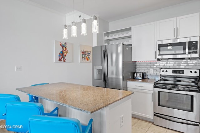 kitchen featuring pendant lighting, white cabinets, a breakfast bar area, light tile patterned floors, and stainless steel appliances