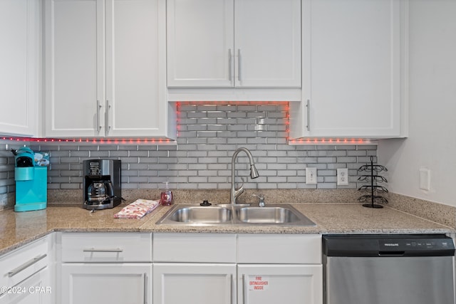 kitchen with white cabinetry, dishwasher, sink, light stone counters, and decorative backsplash