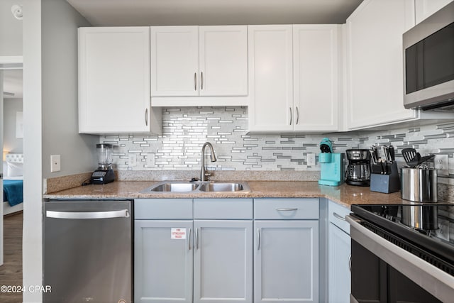 kitchen with backsplash, white cabinetry, sink, and appliances with stainless steel finishes