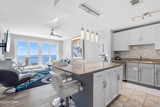 kitchen with sink, hanging light fixtures, ceiling fan, tasteful backsplash, and a kitchen island