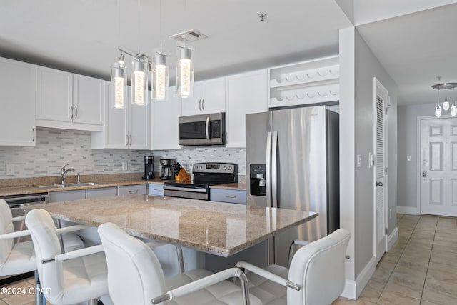 kitchen with white cabinets, pendant lighting, a kitchen island, and stainless steel appliances