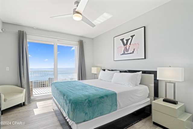 bedroom featuring ceiling fan, light hardwood / wood-style floors, a water view, and access to outside