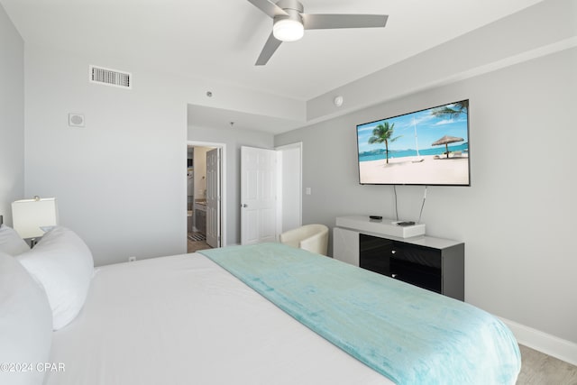 bedroom with wood-type flooring, connected bathroom, and ceiling fan