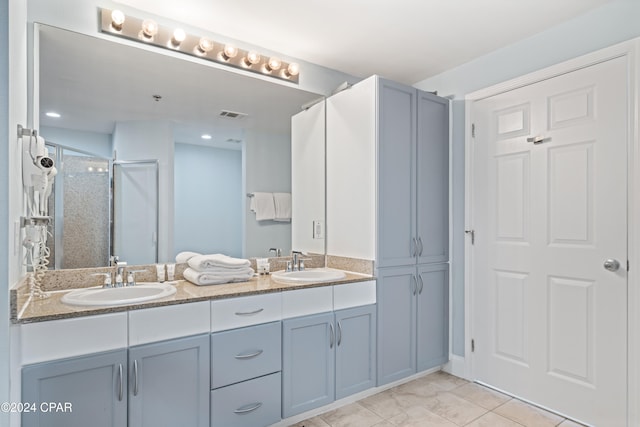 bathroom featuring a shower with door, vanity, and tile patterned flooring