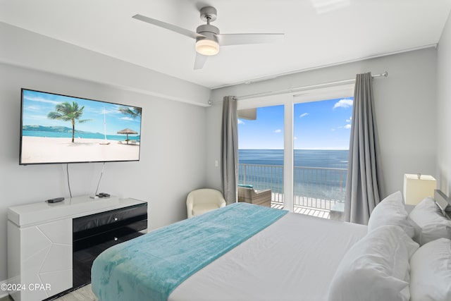 bedroom with access to outside, a water view, ceiling fan, and hardwood / wood-style flooring