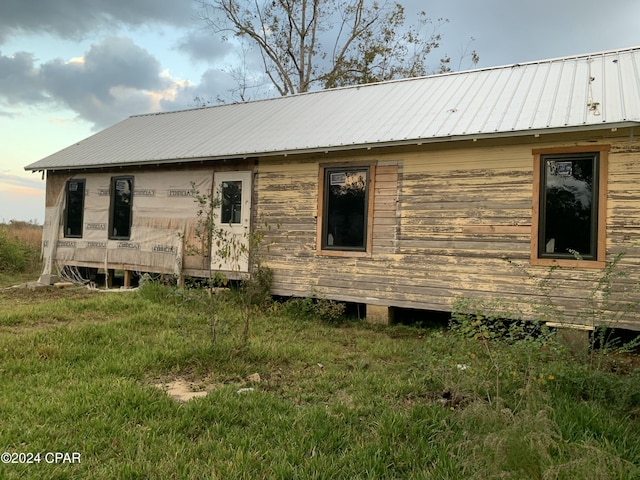 rear view of property with a lawn and metal roof