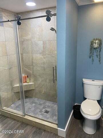 bathroom featuring hardwood / wood-style flooring, toilet, and walk in shower