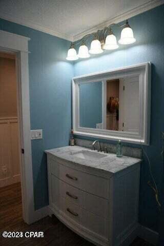 bathroom with vanity, wood-type flooring, ornamental molding, and a textured ceiling