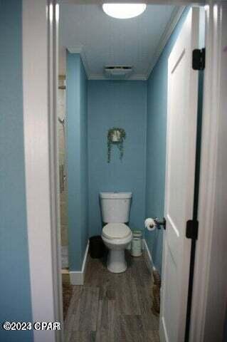 bathroom with ornamental molding, wood-type flooring, and toilet