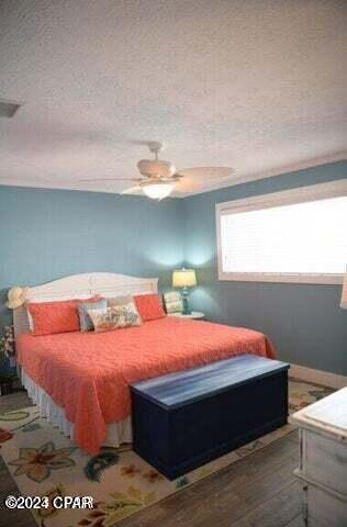 bedroom with ceiling fan, hardwood / wood-style floors, and a textured ceiling