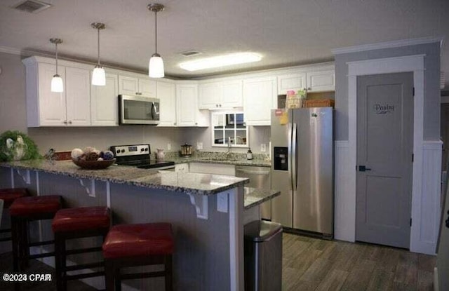 kitchen with appliances with stainless steel finishes, dark wood-type flooring, crown molding, pendant lighting, and white cabinetry