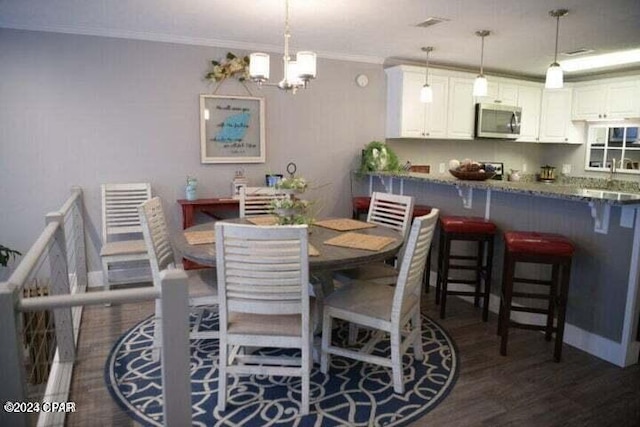 dining room featuring crown molding, sink, a notable chandelier, and dark hardwood / wood-style flooring