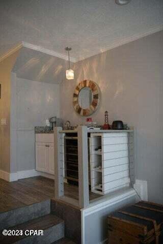 bar with a textured ceiling, hardwood / wood-style flooring, and crown molding