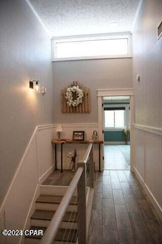 hallway featuring a textured ceiling, wood-type flooring, a healthy amount of sunlight, and a high ceiling