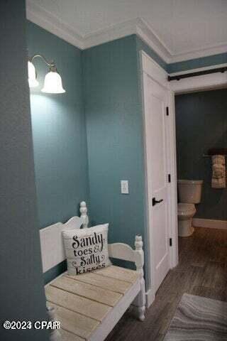 bathroom with crown molding, toilet, and hardwood / wood-style flooring