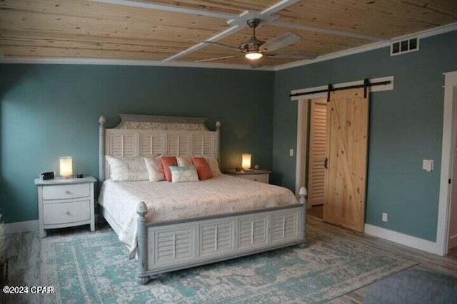 bedroom featuring hardwood / wood-style floors, crown molding, ceiling fan, a barn door, and wood ceiling