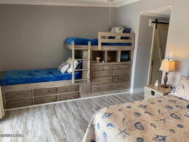 bedroom featuring light hardwood / wood-style floors, a barn door, and ornamental molding