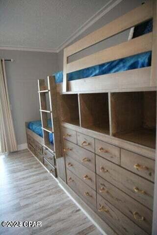 unfurnished bedroom featuring a textured ceiling, hardwood / wood-style flooring, and ornamental molding