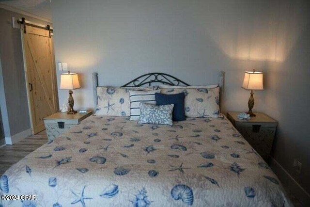 bedroom featuring a barn door and hardwood / wood-style flooring