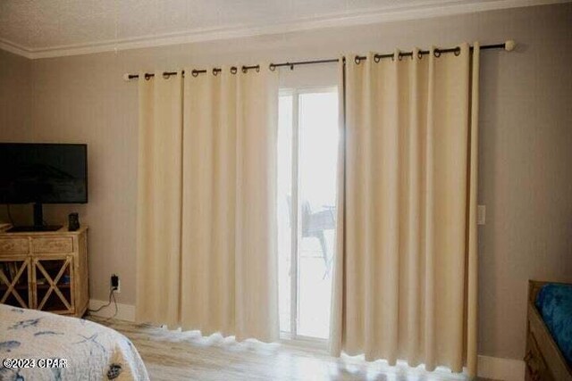 bedroom featuring a textured ceiling, light wood-type flooring, and ornamental molding