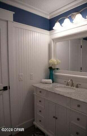 bathroom with a textured ceiling, vanity, and crown molding