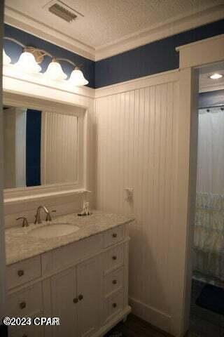 bathroom featuring vanity, a textured ceiling, and crown molding