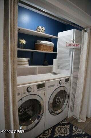 clothes washing area with independent washer and dryer and hardwood / wood-style flooring