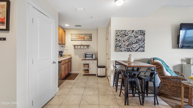 kitchen featuring stainless steel dishwasher, light tile patterned floors, and sink