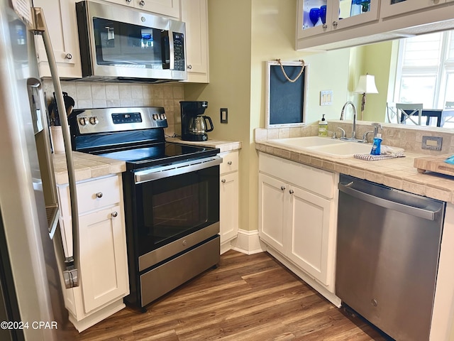 kitchen featuring sink, dark wood-type flooring, white cabinetry, stainless steel appliances, and decorative backsplash