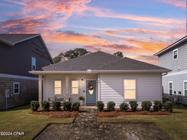 view of front of home with a lawn and central AC