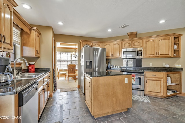 kitchen with light brown cabinets, a center island, dark stone counters, sink, and appliances with stainless steel finishes