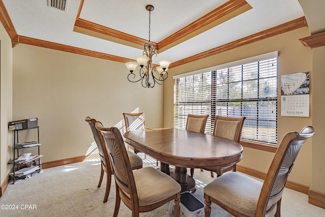 dining room featuring light carpet, an inviting chandelier, a raised ceiling, ornamental molding, and a textured ceiling