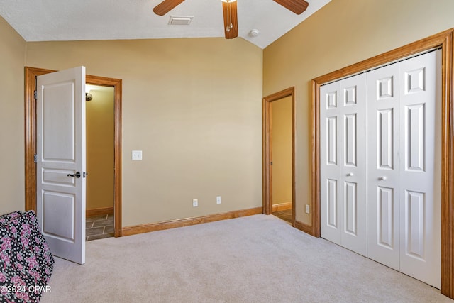 unfurnished bedroom with ceiling fan, lofted ceiling, light carpet, and a closet