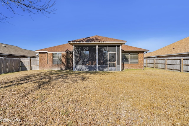 rear view of house with a sunroom and a yard