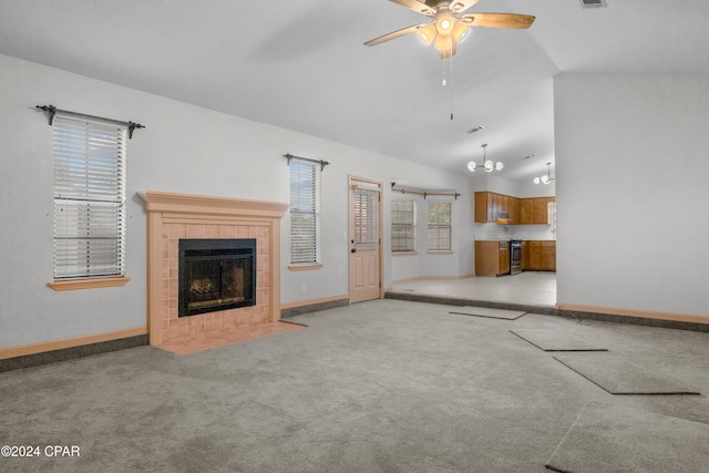 unfurnished living room featuring a tiled fireplace, a wealth of natural light, light colored carpet, and vaulted ceiling