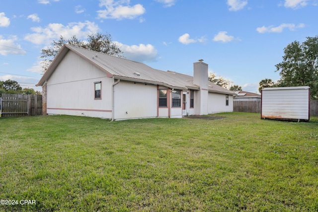 rear view of property featuring a yard and a storage shed