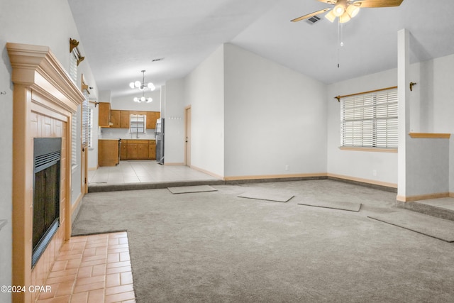 unfurnished living room featuring ceiling fan with notable chandelier, light tile patterned flooring, and high vaulted ceiling