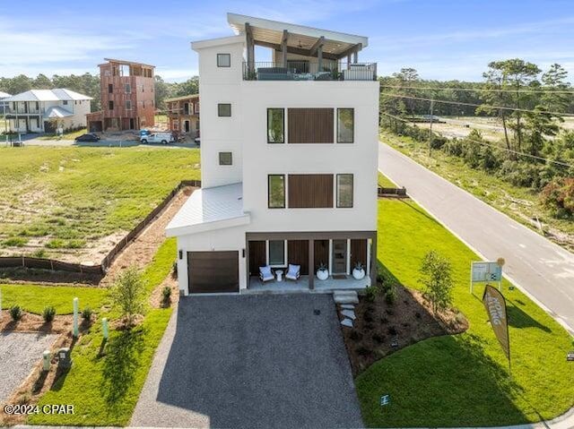 modern home with a balcony, a front lawn, covered porch, and a garage