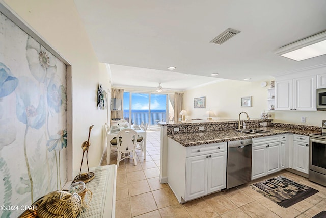 kitchen with white cabinets, a water view, sink, appliances with stainless steel finishes, and kitchen peninsula