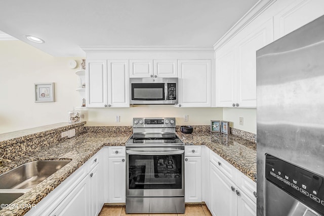 kitchen featuring stainless steel appliances, white cabinetry, and dark stone countertops