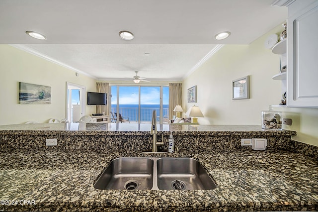 kitchen featuring crown molding, sink, ceiling fan, dark stone countertops, and white cabinetry