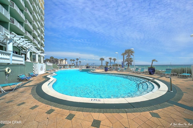 view of pool featuring a patio and a water view