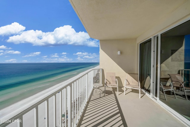 balcony with a water view and a view of the beach