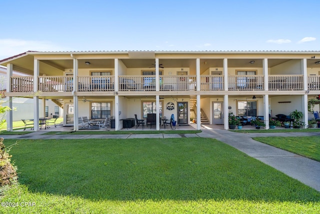 back of property featuring ceiling fan, a balcony, a patio area, and a lawn